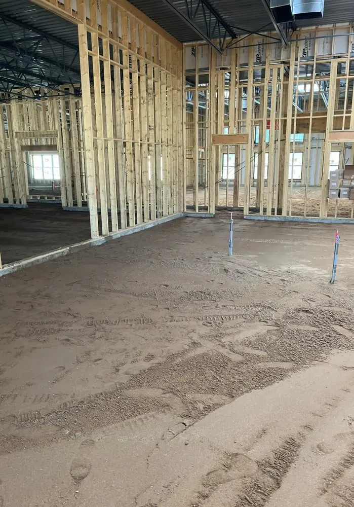 Compacted floor prep ready for slab pour inside a steel-and-wood framed structure