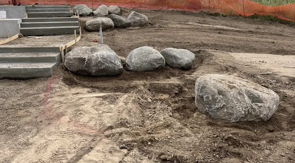 Boulder placement and grading next to fresh poured concrete steps on a Minnesota landscape build