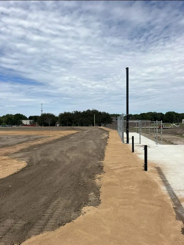Site preparation and gravel road grading along a freshly fenced commercial lot